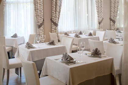 Elegancka restauracja. Na stołach czeka zastawa, a nad nimi wiszą nowoczesne lampy.