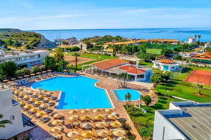 Kompleks hotelowy z basenem i kortami tenisowymi, widok z góry na morze.
