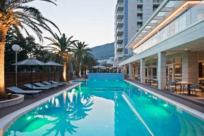 Basen z palmami, w tle budynek hotelu.