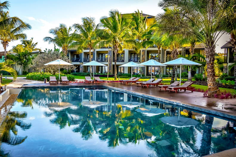 Basen w tropikalnym kurorcie. Wokół palmy i leżaki.