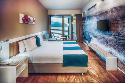 Pokój hotelowy z łóżkiem, balkonem i tapetą w stylu marynistycznym.