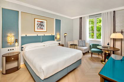 Pokój hotelowy z dużym łóżkiem, oknem i częścią wypoczynkową.