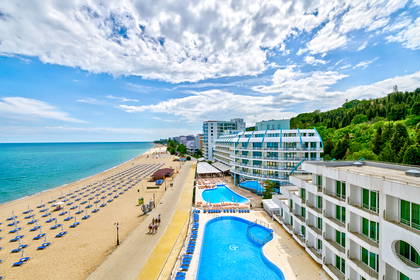 Hotel z basenami przy plaży w słoneczny dzień.