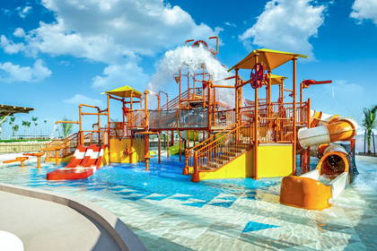 Kolorowy park wodny ze zjeżdżalniami w odcieniach żółci i pomarańczy.
