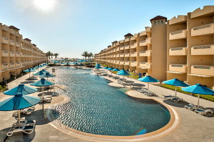 Basen w ośrodku wypoczynkowym z parasolami. W tle budynki.