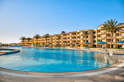 Kompleks hotelowy z basenem i palmami.