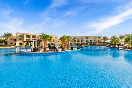 Kompleks hotelowy z basenem, palmami i mostkiem.