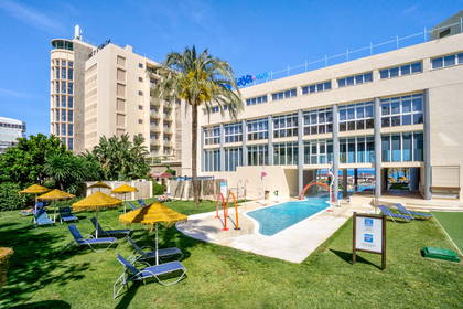 Hotel z basenem dla dzieci i leżakami do opalania.
