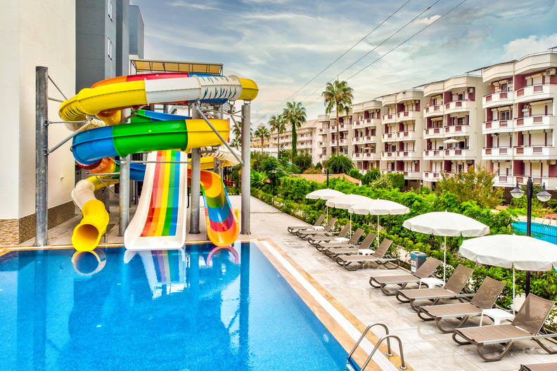 Basen z kolorowymi zjeżdżalniami i leżakami przy hotelu.