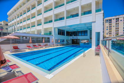 Basen hotelowy z leżakami i parasolami.