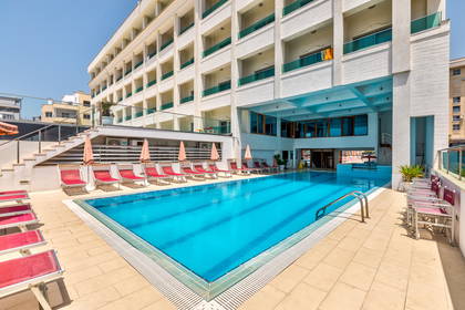 Basen hotelowy z leżakami i parasolami.