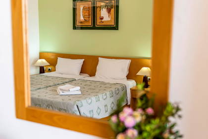 Dwa łóżka w pokoju hotelowym widoczne w lustrze.