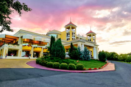 Żółty budynek hotelu Bellevue i zielony trawnik w promieniach różowego zachodzącego słońca.