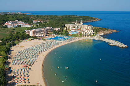 Plaża z parasolami i leżakami, hotele w tle, widok z lotu ptaka.