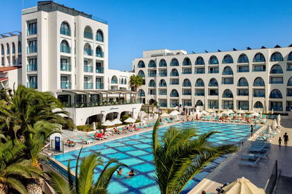 Hotel z basenem, palmami i leżakami.