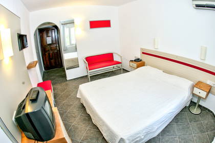 Pokój hotelowy z białym łóżkiem, sofą i telewizorem.