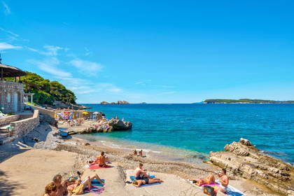 Plaża w słoneczny dzień i opalający się ludzie.