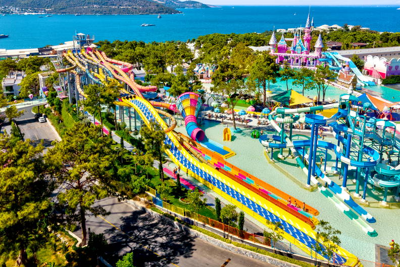 Panorama parku wodnego z kolorowymi zjeżdżalniami i basenami.