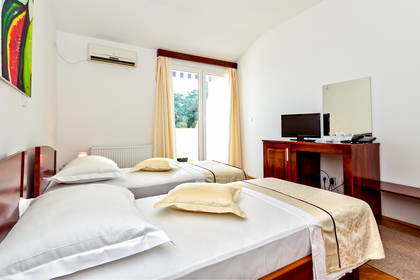 Pokój hotelowy z dwoma łóżkami, telewizorem i biurkiem.