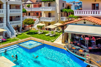 Kompleks hotelowy z basenem, leżakami i barem przy basenie.