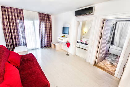 Pokój hotelowy z sofą i telewizorem. Widok na łazienkę i sypialnię.