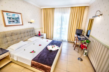 Pokój hotelowy z łóżkiem, kwiatami i szampanem.