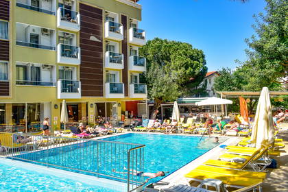 Basen hotelowy z leżakami i wypoczywającymi gośćmi.