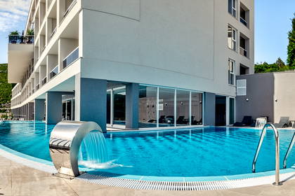 Basen hotelowy z kaskadą i leżakami.