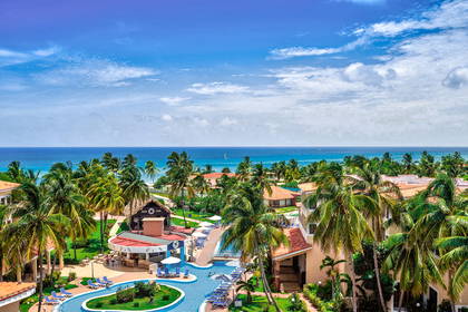 Resort z basenem i palmami. W tle ocean.