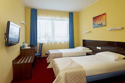 Pokój hotelowy z dwoma łóżkami, biurkiem i telewizorem.