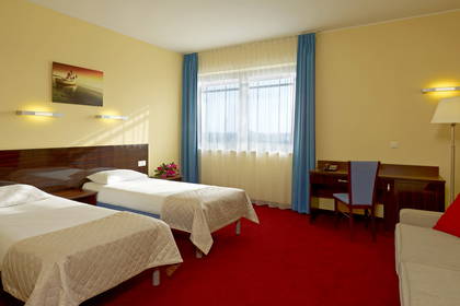 Pokój hotelowy z dwoma łóżkami, biurkiem i kanapą.