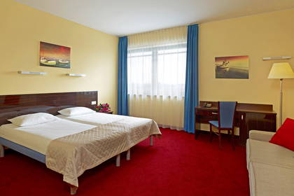 Pokój hotelowy z dwoma łóżkami, biurkiem i kanapą.
