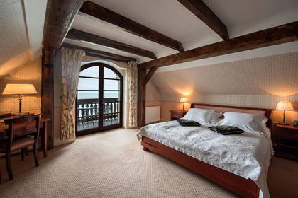 Pokój hotelowy z łóżkiem, biurkiem i balkonem z widokiem na morze.