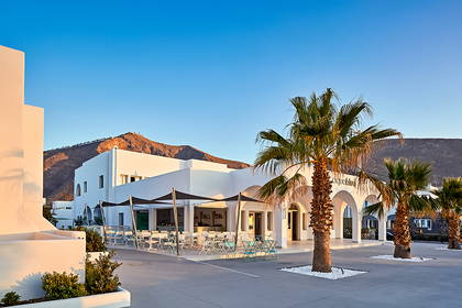 Restauracja w białym budynku z palmami na Santorini.