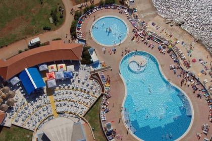 Widok z góry na baseny, plażę i teren rekreacyjny.