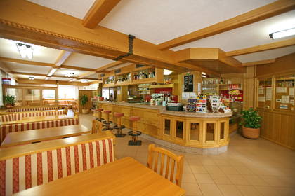 Wnętrze restauracji: bar, stoliki i elementy z drewna.