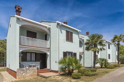 Niebieskie budynki apartamentowe z balkonami, otoczone palmami.