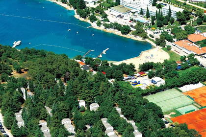 Widok z góry na zatokę z plażą, hotelami, domami i kortami tenisowymi.
