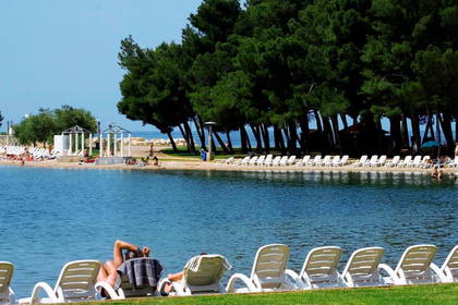 Plaża z leżakami i wypoczywającymi ludźmi.