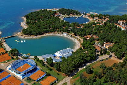Widok z lotu ptaka na plażę z hotelami i kortami tenisowymi.