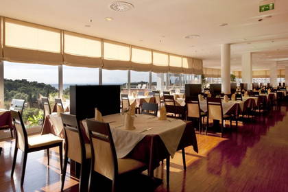 Jasne wnętrze restauracji z oknami i nakrytymi stolikami.