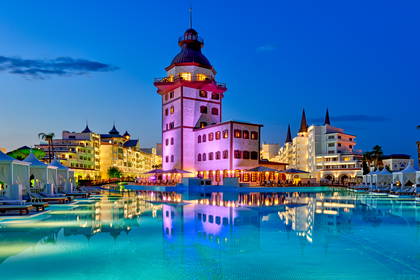 Luksusowy hotel z basenem oświetlonym o zmierzchu.