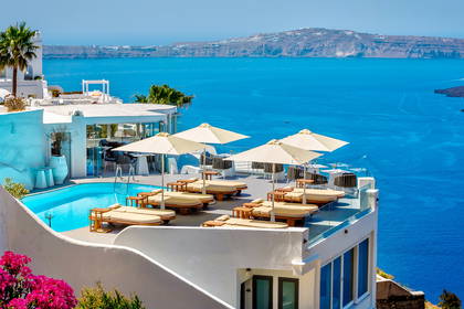Santorini: basen z leżakami i widok na morze.