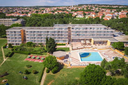 Widok z lotu ptaka na hotel z basenem i kortami tenisowymi.