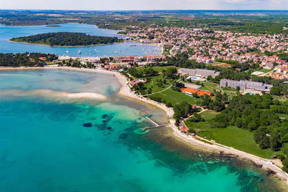 Widok z lotu ptaka na turkusowe wybrzeże z plażami i zabudową miejską.