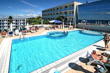 Basen hotelowy z leżakami i wypoczywającymi gośćmi.