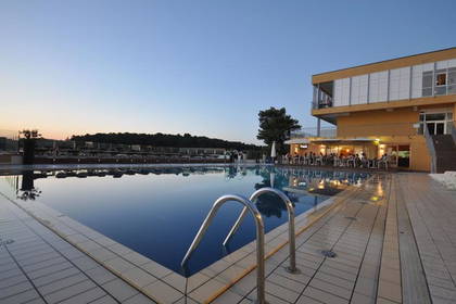 Basen hotelowy o zmierzchu, w tle budynek.