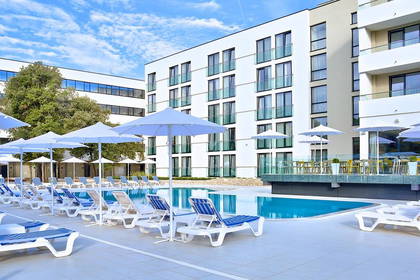 Basen hotelowy z leżakami i parasolami.