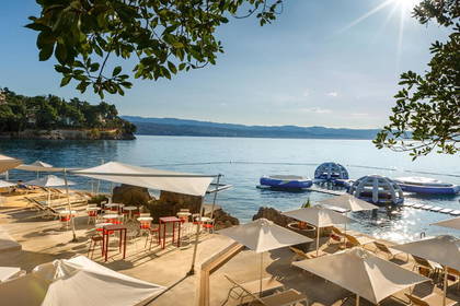 Słoneczny dzień na plaży. Białe parasole i leżaki czekają na turystów.