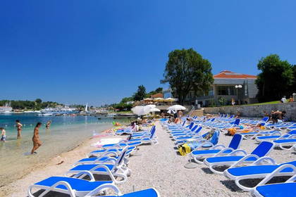 Plaża z leżakami i kąpiący się w morzu ludzie.